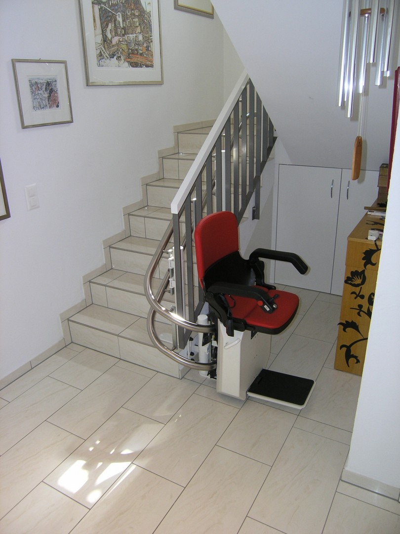 07-Treppenlift-Sitzlift-180-Grad-Kurve Treppenlift in unterer Haltestelle, seitlich der Treppe, nach 180°-Kurve