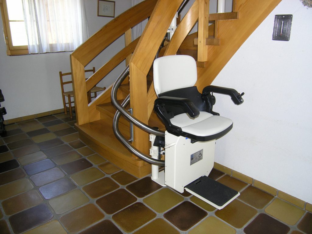 Treppenlift Holztreppe innen, Haltestelle unten, Sitzlift offen und fahrbereit