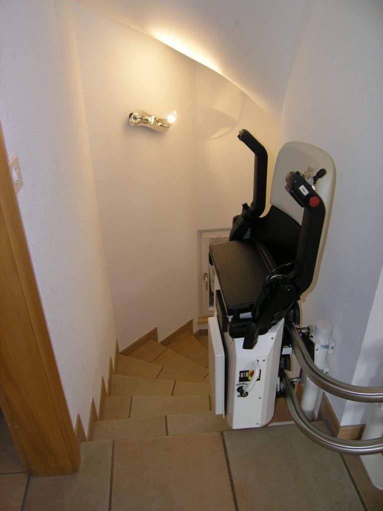 Treppenlift über mehrere Etagen, Sitzlift an der Zwischenhaltestelle zusammengeklappt